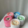 Five flower-shaped candles in colored glass holders on a table