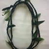Braided dark green floral lei with scattered leaves