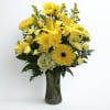 Sunlit yellow lilies and gerbera daisies take center stage in this cheerful