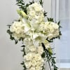 White floral cross on a stand with lilies and roses