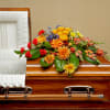 Colorful floral spray on a wooden casket beside a white interior lining