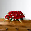 Red and white floral casket spray on a wooden coffin