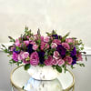 A lush mound of pink roses and deep purple blooms creates an