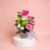 Pink and white flowers in a striped vase with a ribbon