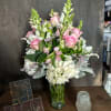 Pink roses and white flowers arranged in a clear glass vase