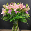 The bouquet is a garden-style mix presented in a clear glass cinched
