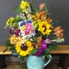 Golden sunflowers and bold orange alstroemeria burst from a light blue ceramic