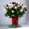 Tall glass vase of red and white roses wrapped with a red ribbon bow