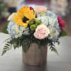 Mixed pastels with hydrangeas, roses, sunflower and buttons arranged in a rose