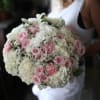 Woman holding a large bouquet of pink and white roses and hydrangeas