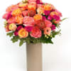 A lush blend of piink, peach and golden blooms, arranged with fresh