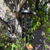 Black memorial wind chime hanging from a tree branch