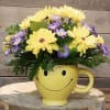 Yellow and purple flowers in a smiley-face mug vase