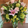 Pink lilies and roses surrounded by lush greens, hydrangea and assorted alstroemeria.