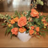 Orange rose arrangement in a white textured vase