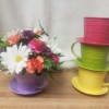 Colorful bouquet in a purple teacup-shaped container beside stacked teacup planters