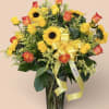 Sunflowers and orange-yellow roses in a clear glass vase with a yellow ribbon