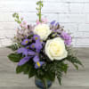 White roses and purple flowers in a glass vase