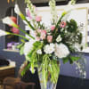 Tall floral arrangement with white calla lilies and pink roses in a glass vase