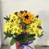 Yellow daisies and an orange sunflower bouquet in a glass vase