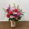 Mixed pink and purple flowers arranged in a white vase