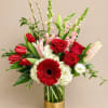 Red roses, tulips, and a gerbera daisy in a gold vase