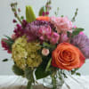 Mixed bouquet with roses, carnations, hydrangea, and lilies in a glass vase