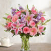 Pink lilies, roses, and daisies in a clear glass vase