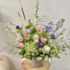 Loose pastel bouquet in a white vase with pink, purple, and white blooms