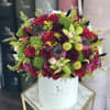Round bouquet of red roses and green orchids in a white hat box