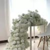 White floral arch draped over a table beside a white chair