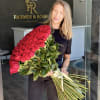 Woman holding a large bouquet of red roses tied with a ribbon