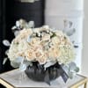 Cream roses and hydrangeas arranged in a black pumpkin vase