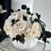 Cream rose bouquet in a white pumpkin vase with dark ribbon
