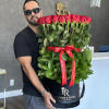 Man holding a large box of red roses with a red ribbon