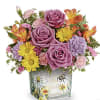 Bouquet of purple roses, yellow daisies, and pink carnations in a painted glass vase