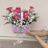 Soft pink roses with white centers spill from a lavender handled gift
