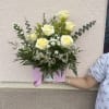 Soft pale yellow roses clustered above a low pink box create an