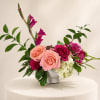A modern, feminine arrangement in peach, raspberry, and soft green, designed with