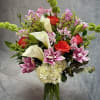 Mixed bouquet with pink lilies, red roses, white calla lilies, and hydrangea in a glass vase