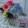 Mixed bouquet with pink gerbera daisies, blue hydrangea, and roses in a glass vase