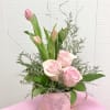 Pink tulips and roses arranged in a pink butterfly tin