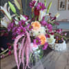 Mixed bouquet with lilies, roses, and purple daisies in a glass vase
