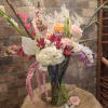 Tall mixed bouquet with pink, white, and orange flowers in a clear vase
