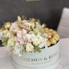Round box of white and blush roses with gold chocolates on top