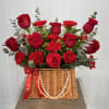 A charming basket arrangement featuring fresh red roses and carnations, accented with