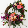 This is a decorative floral wreath arranged on a black metal easel.