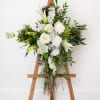This is an elegant, all-white floral arrangement displayed on a metal green