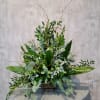 Tall green floral arrangement in a dark rectangular vase