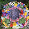 Round bouquet with pink and yellow roses and a large purple succulent center